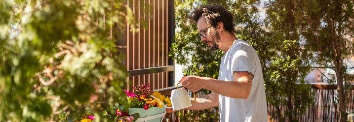 Mann gießt Pflanzen auf der Dachterrasse